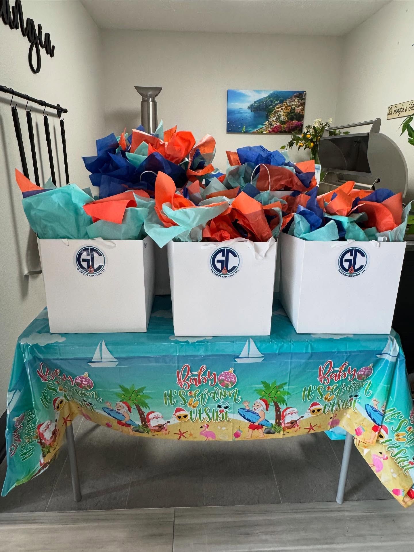 Three white boxes with colorful tissue paper on a table with a beach-themed tablecloth.