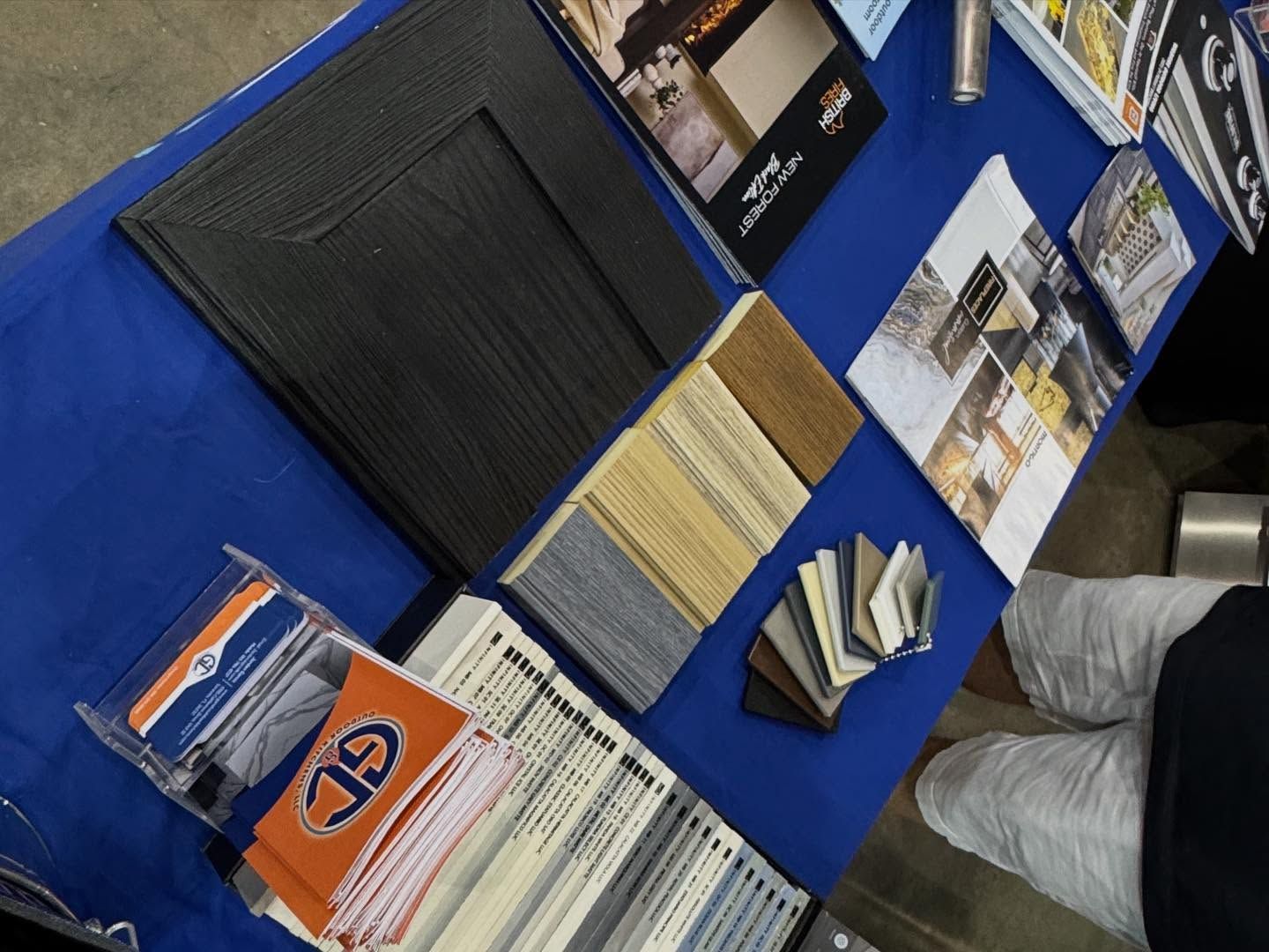 Table display of various flooring samples and promotional materials on a blue tablecloth.