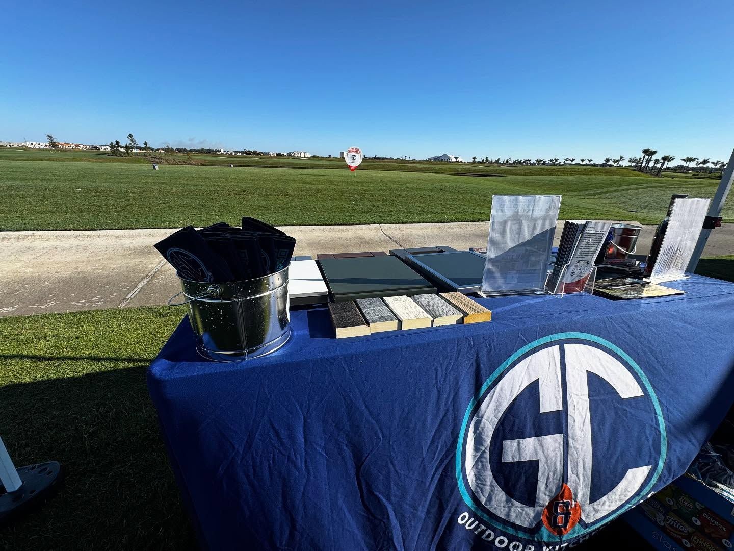 A table with stone samples and a logo in an outdoor setting on a sunny day.