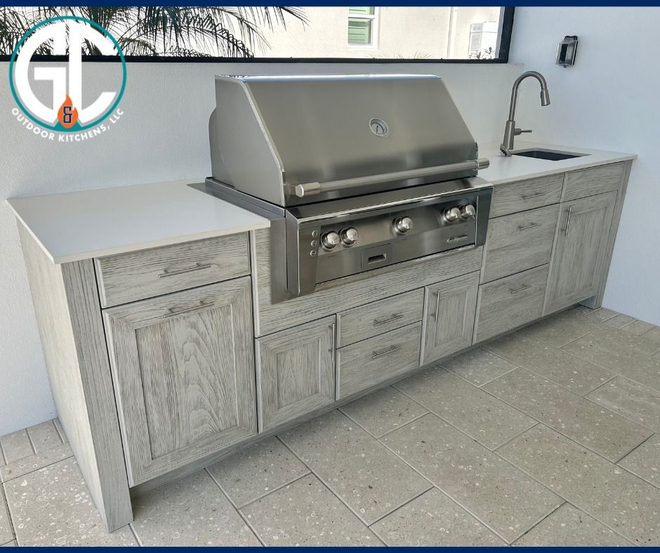 Outdoor kitchen with stainless steel grill, cabinets, sink, and countertop.