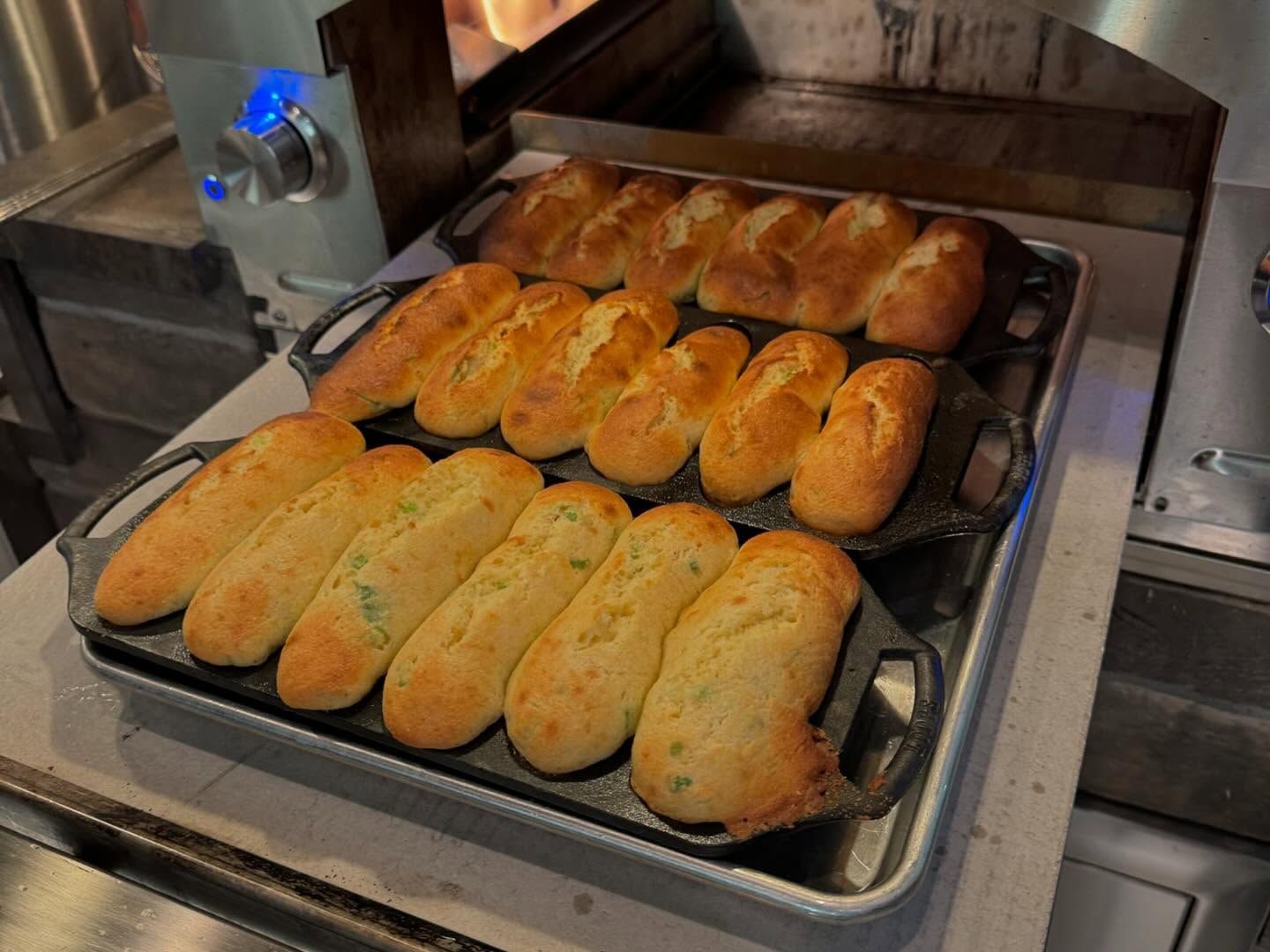 Baked rolls on three tiered trays, in a kitchen setting.