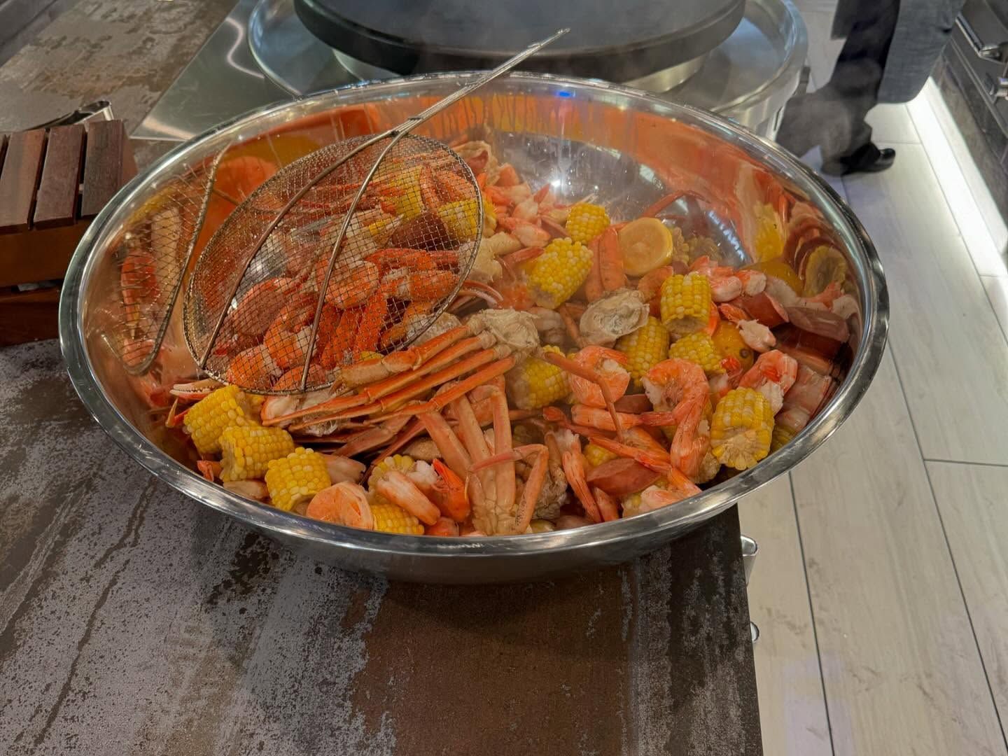 Large bowl of seafood: crab legs, shrimp, corn, and lemon slices.