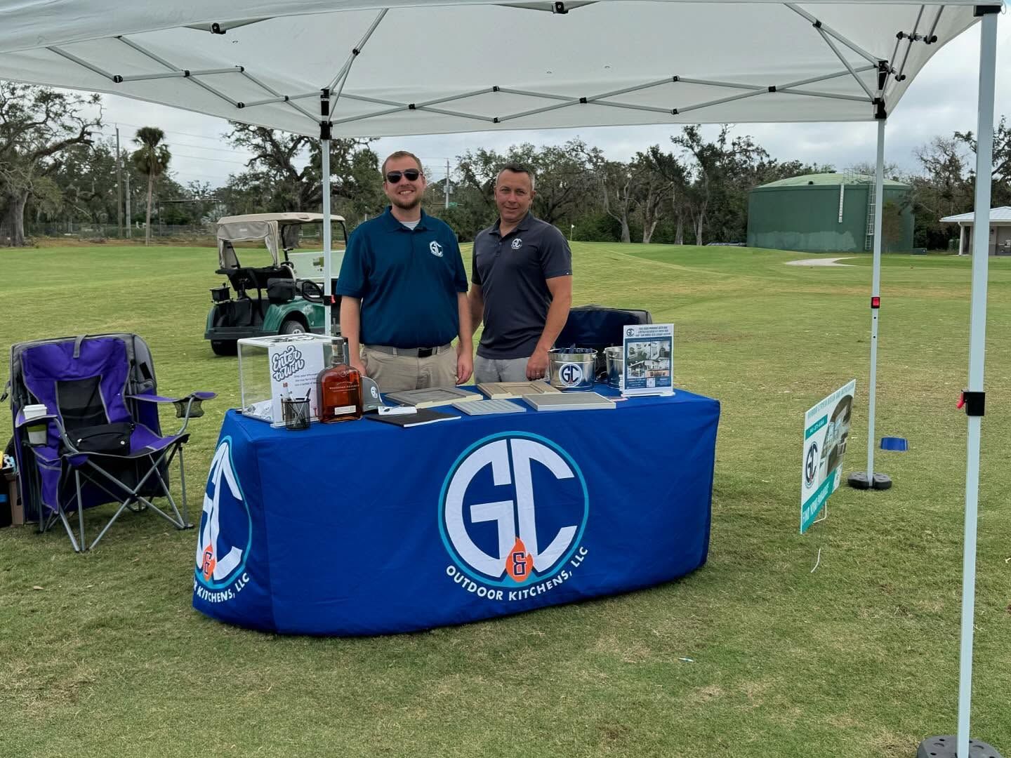 Two men at a blue table under a canopy with 