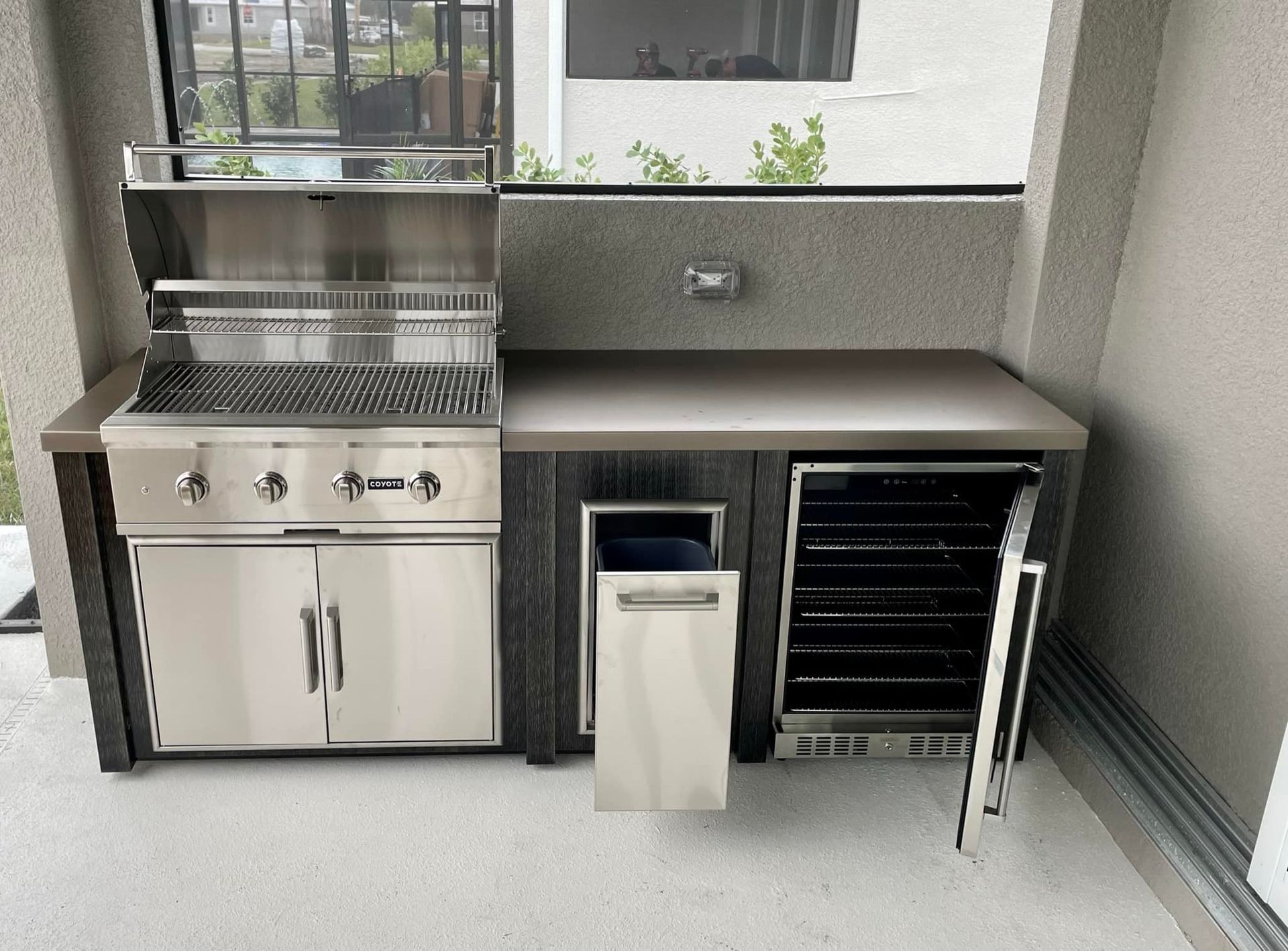 Outdoor kitchen with stainless steel grill, side prep space, and built-in cooler.