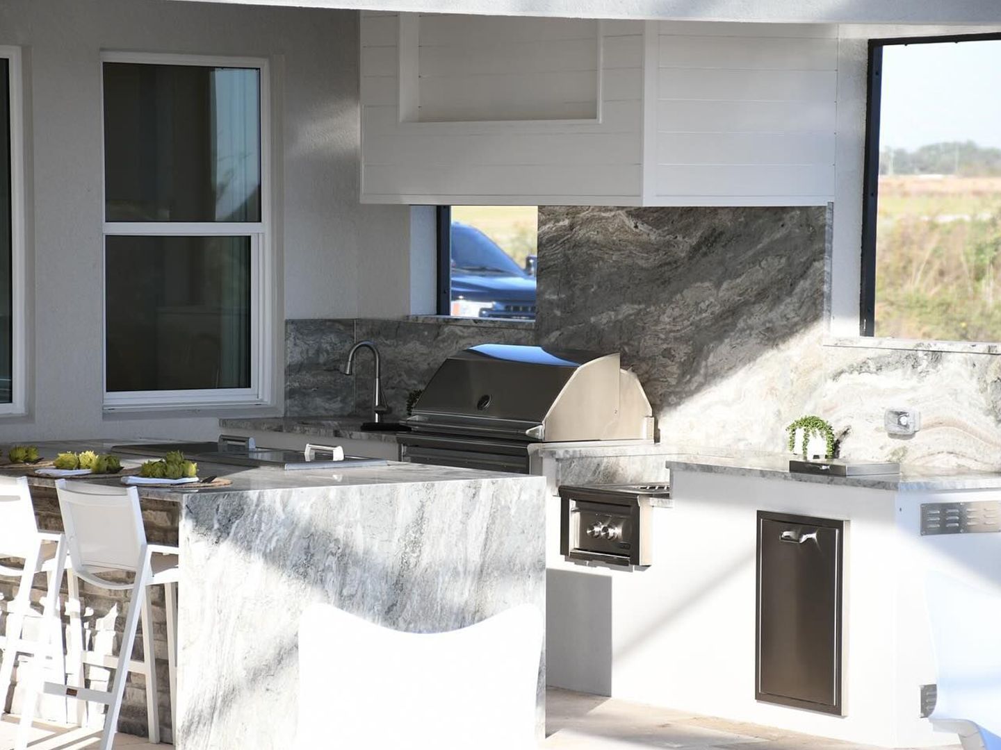 Outdoor kitchen with grill, sink, and bar seating in a modern patio setting