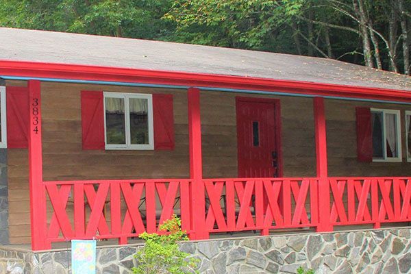 A wooden house with red shutters and a red porch