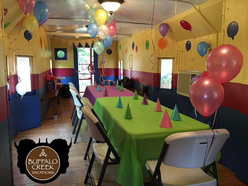 A room filled with tables and chairs decorated for a birthday party.
