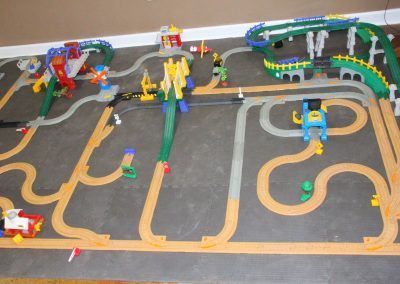 A toy train set is sitting on a carpeted floor