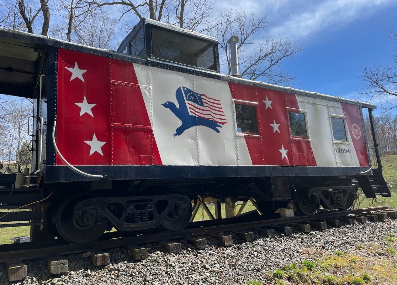 A red , white and blue train car is parked on the tracks.