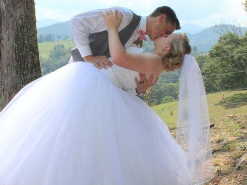 A bride and groom are kissing in front of a tree.