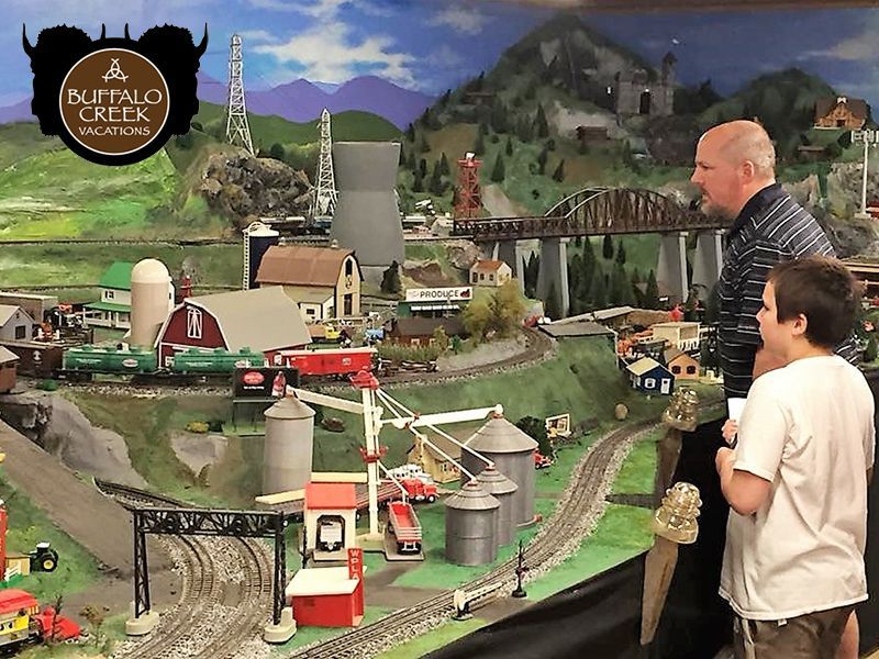 Two people are looking at a model train set in buffalo creek