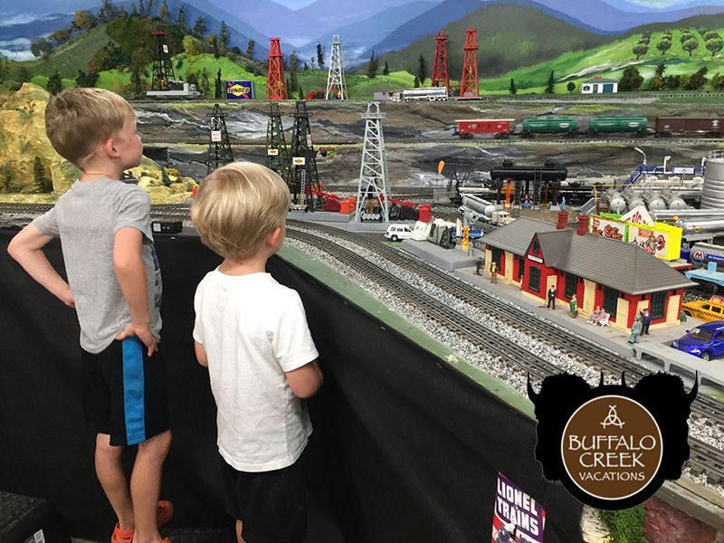 Two young boys are looking at a model train set.