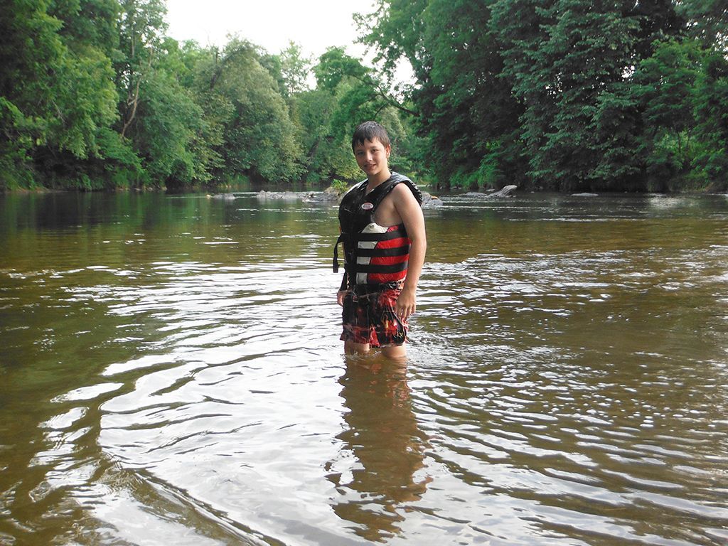 A man in a life jacket is standing in the water