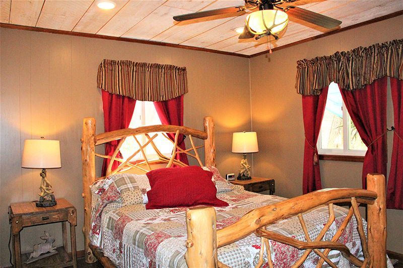 A bedroom with a log bed and a ceiling fan.