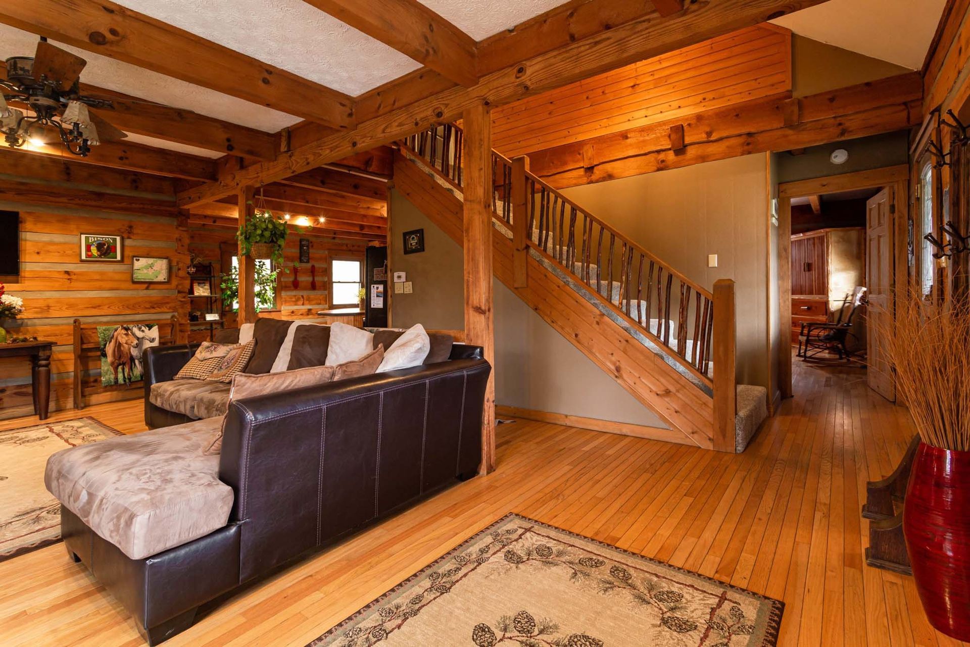 A living room with a couch and stairs in a log cabin.