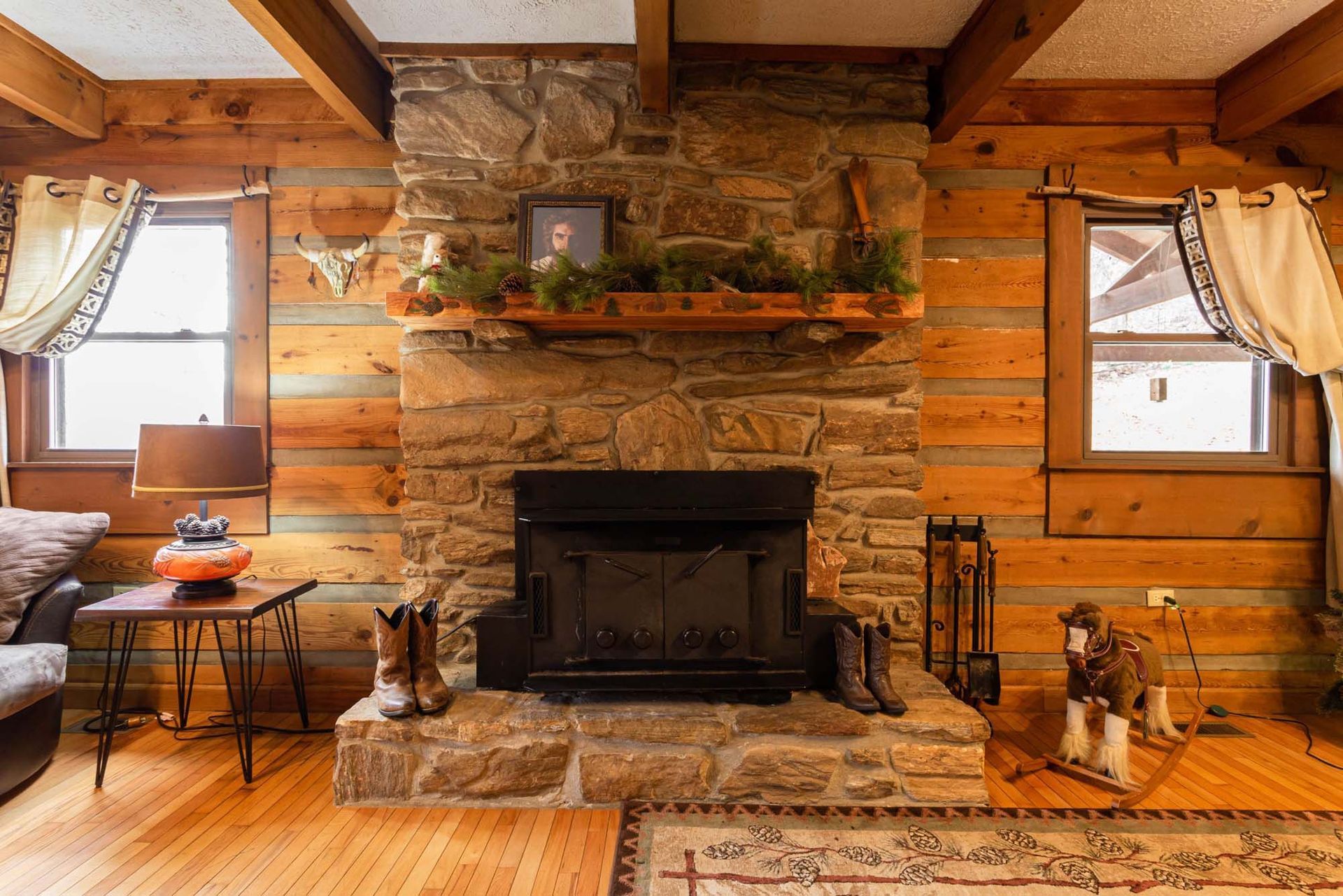 A living room in a log cabin with a stone fireplace.