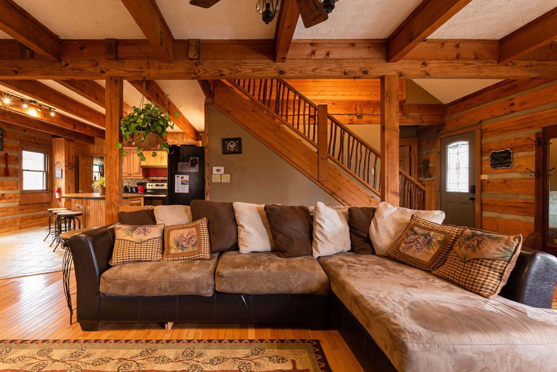 A living room in a log cabin with a couch and stairs.