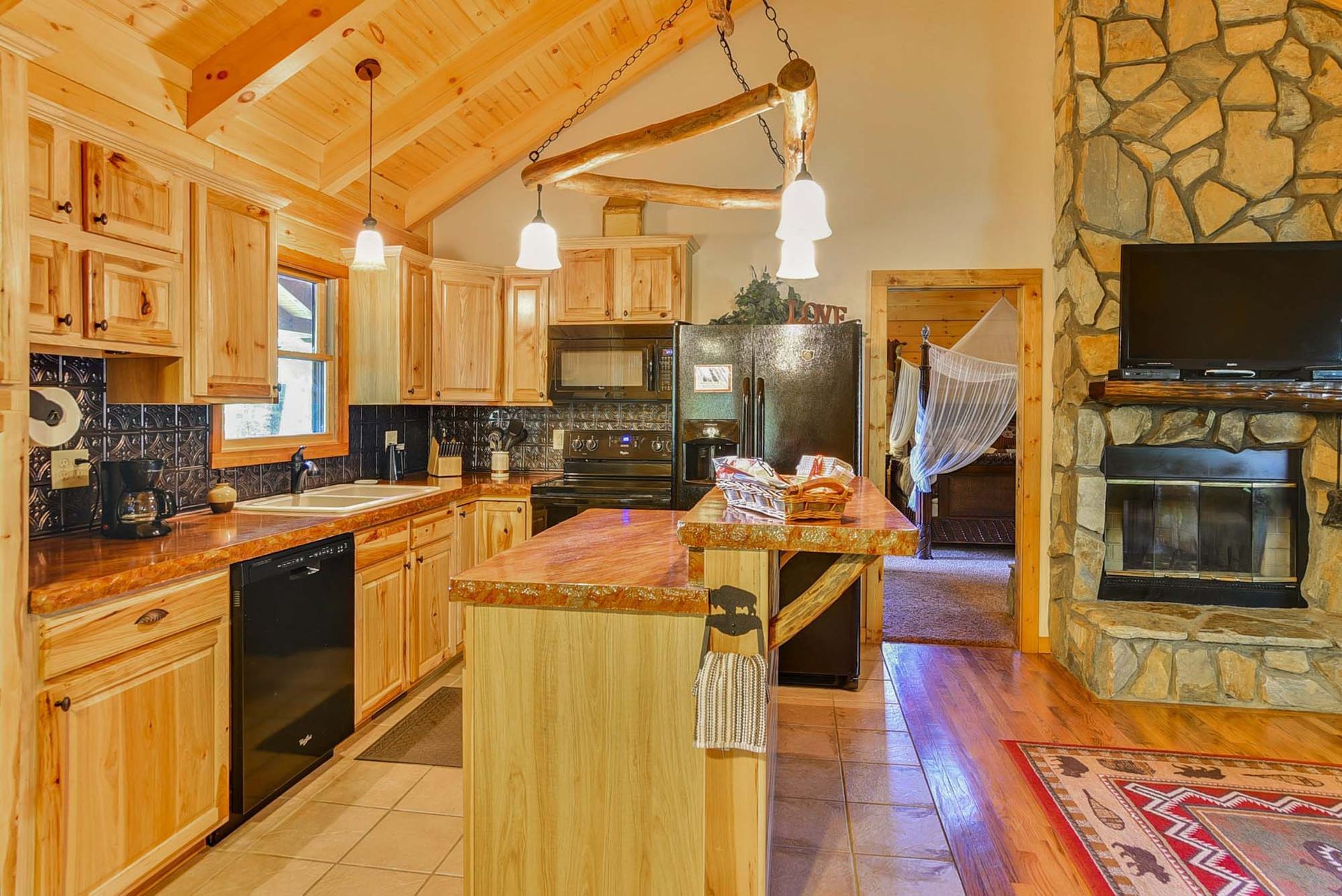 A kitchen in a cabin with wooden cabinets and a fireplace.