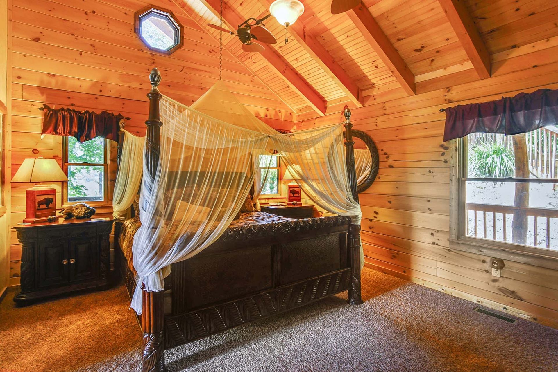 A bedroom in a log cabin with a canopy bed and a ceiling fan.