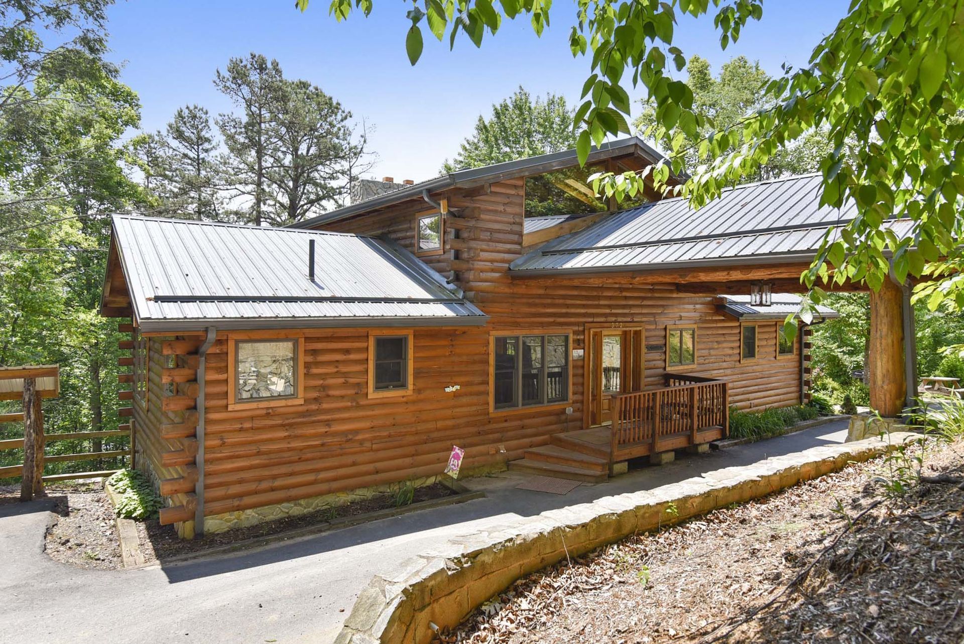 A large log cabin with a metal roof is surrounded by trees.