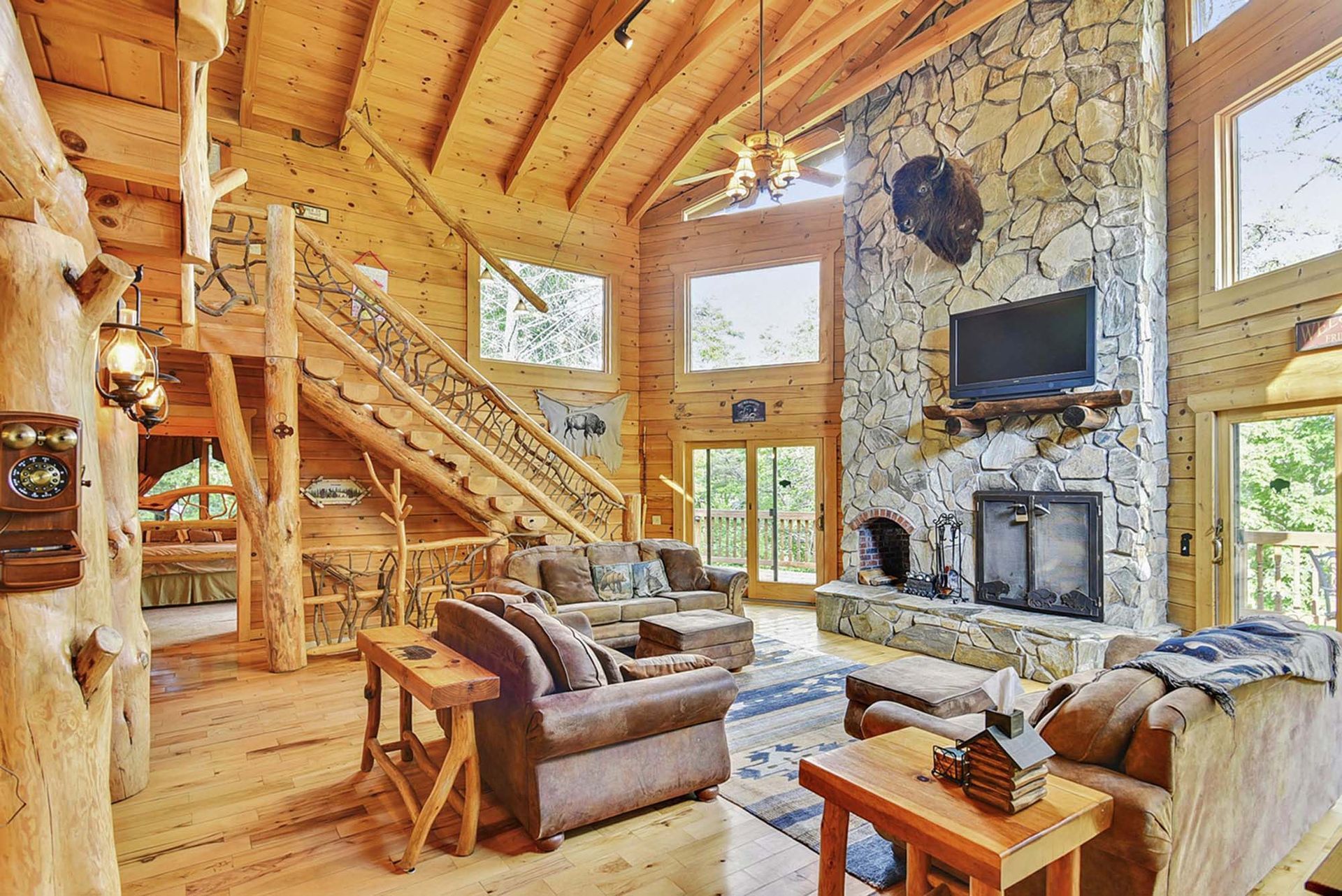 A living room in a log cabin with a fireplace and stairs.