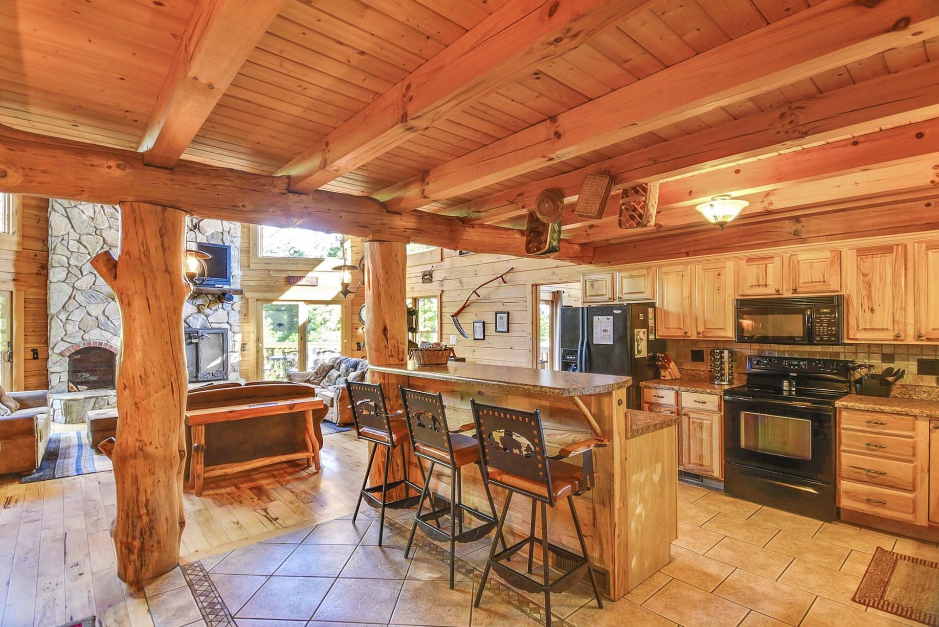 A kitchen in a log cabin with a bar and stools.