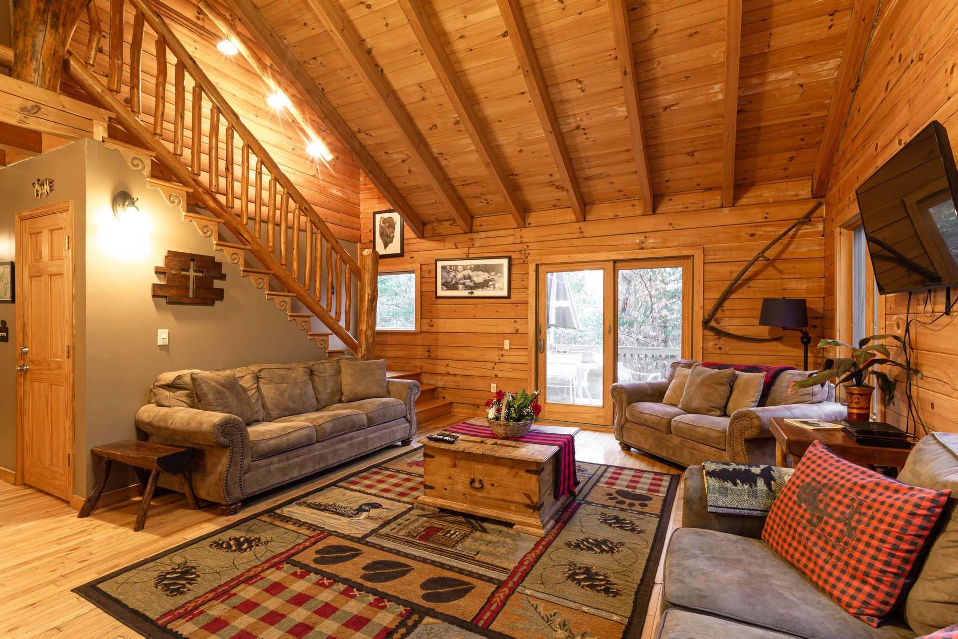 A living room in a log cabin with a couch and stairs.