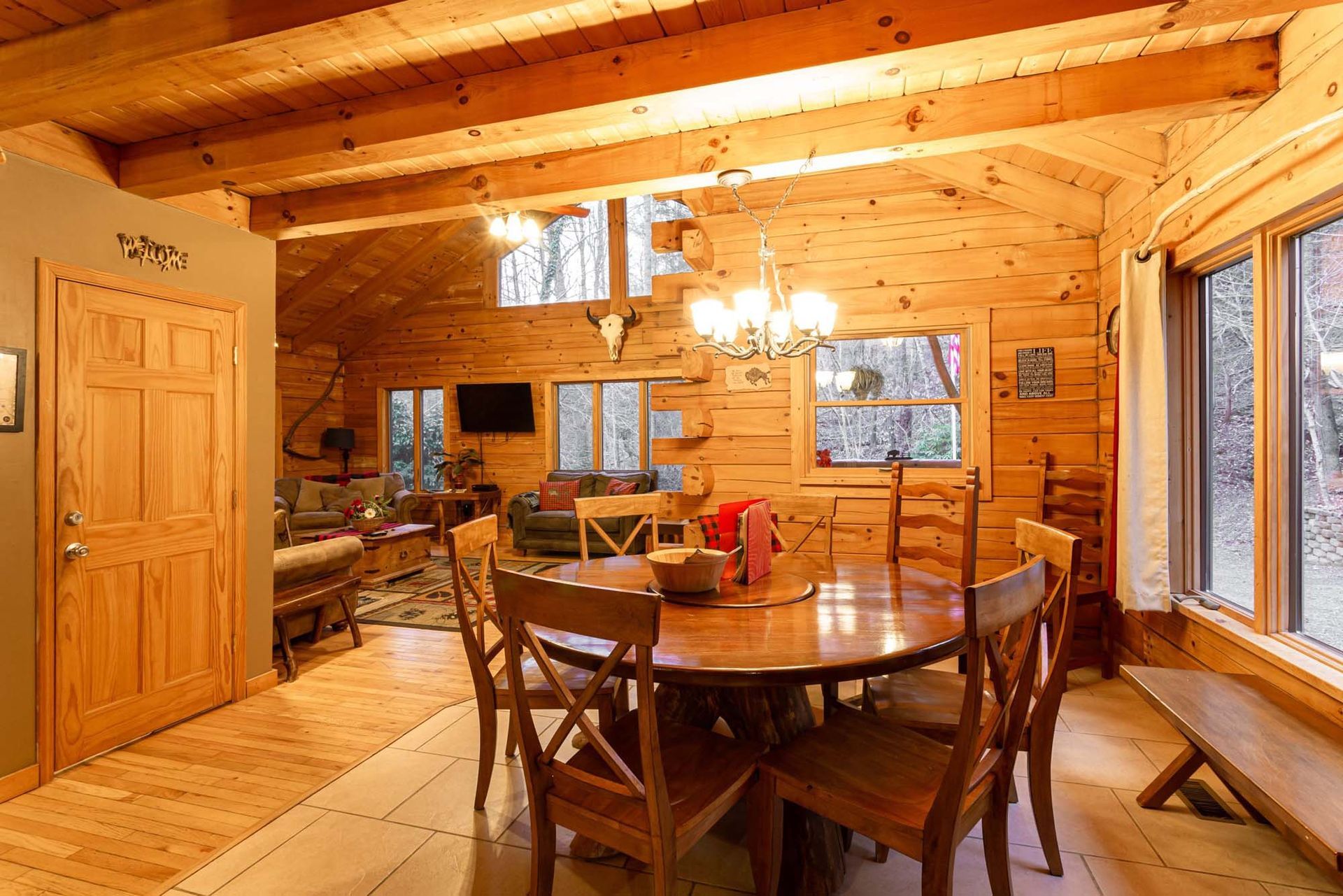 A dining room in a log cabin with a round table and chairs.
