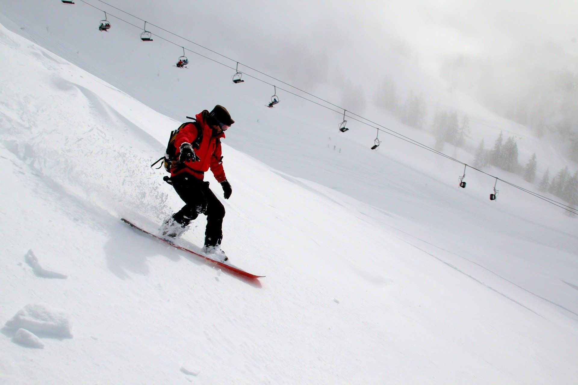 A person is riding a snowboard down a snow covered slope.