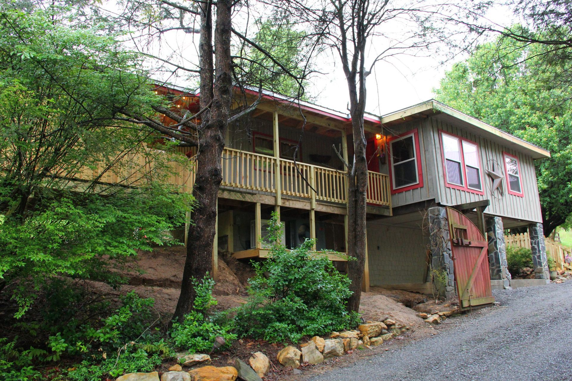 A house with a large deck is surrounded by trees.