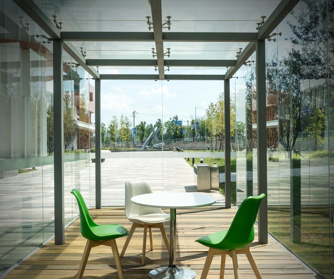 A table with green chairs under a glass canopy