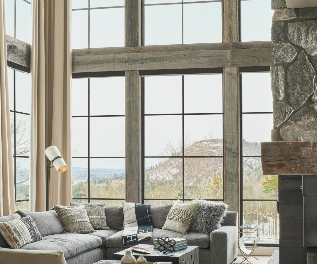 A living room with a couch , fireplace , and lots of windows.