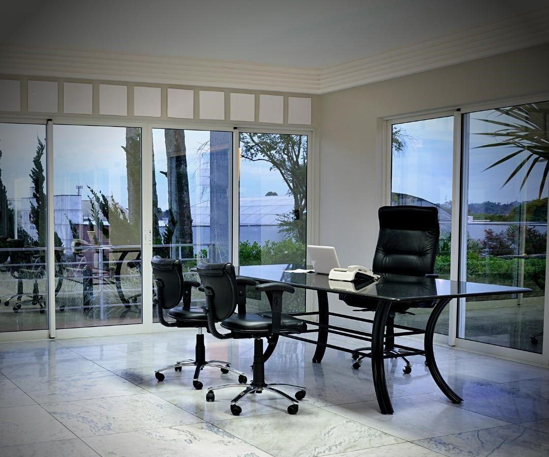 A room with a desk and chairs and a lot of windows