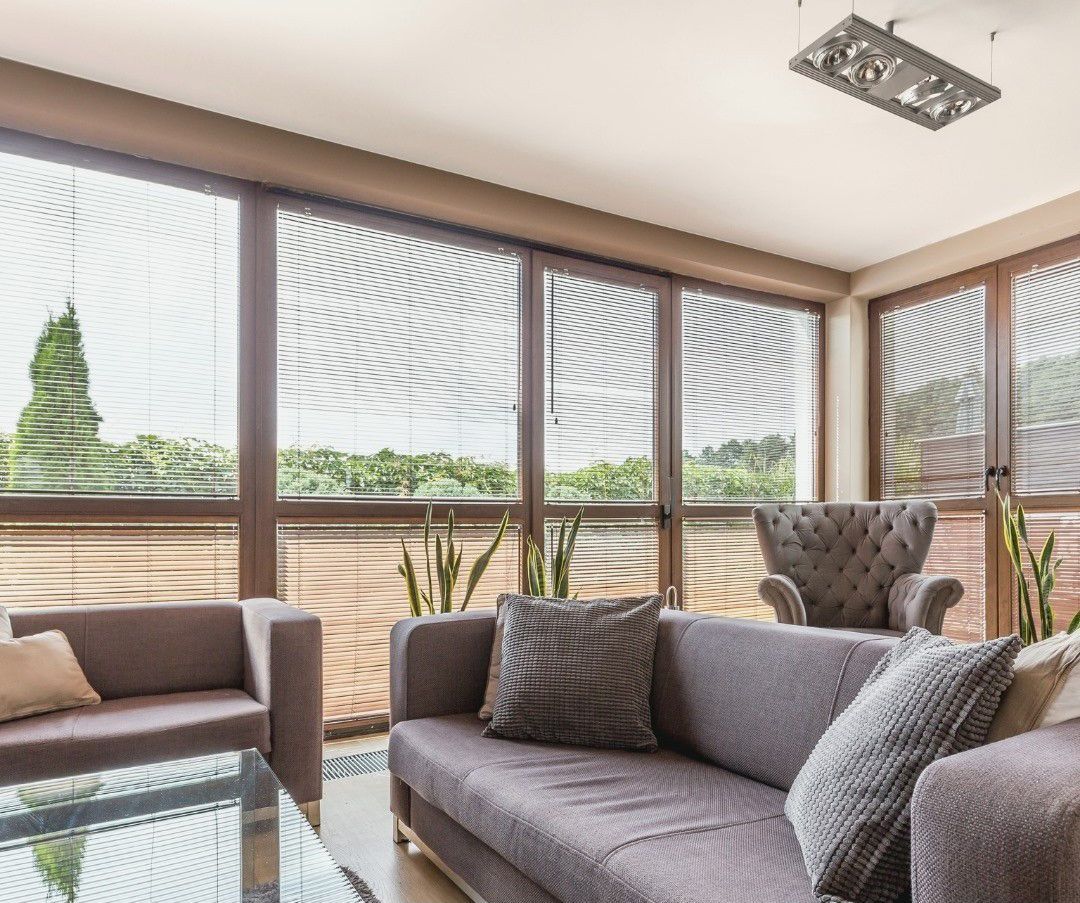 A living room with a couch , chair , coffee table and lots of windows.