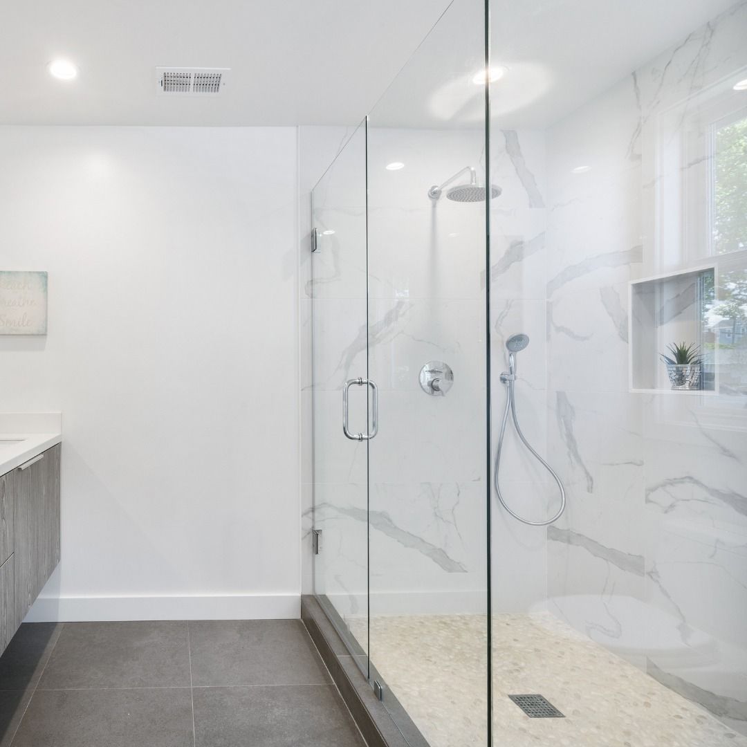 A bathroom with a walk in shower with a glass door.