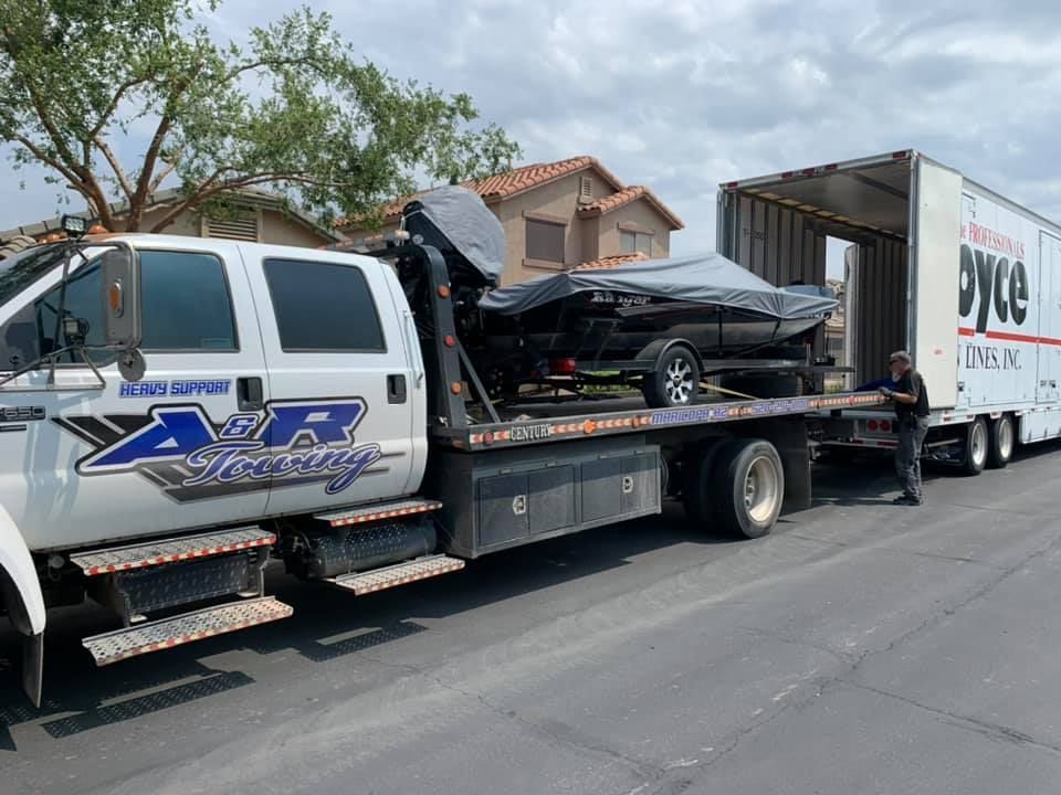 A tow truck is carrying a car and a trailer.