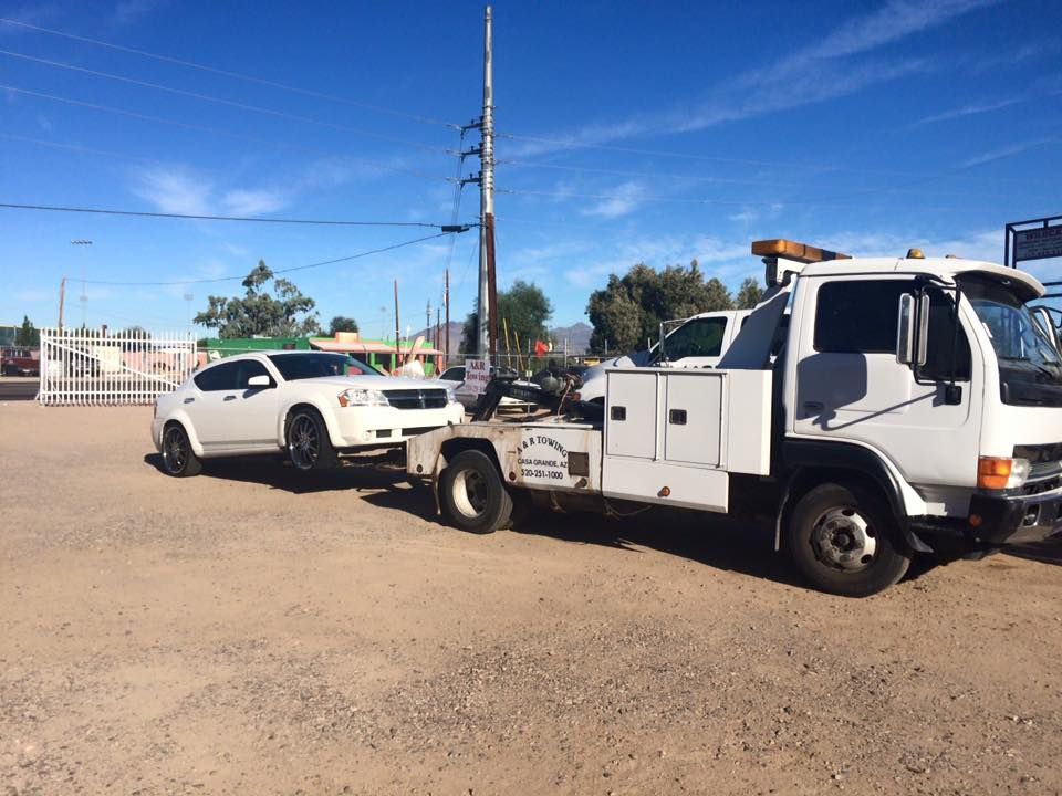 A white tow truck is towing a white car