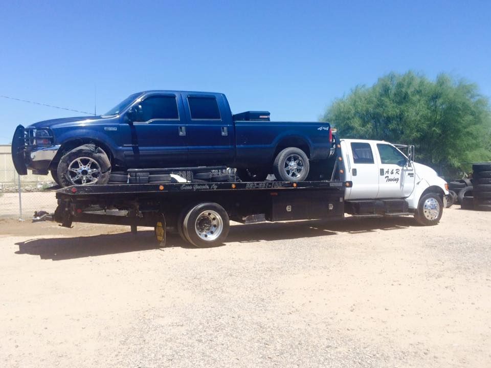 A blue truck is sitting on top of a tow truck.