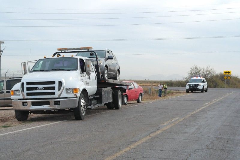 A tow truck is carrying a car on the back of it.