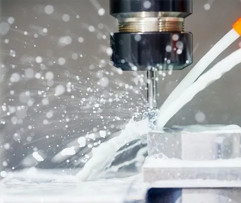 A machine is cutting a piece of metal with liquid coming out of it.