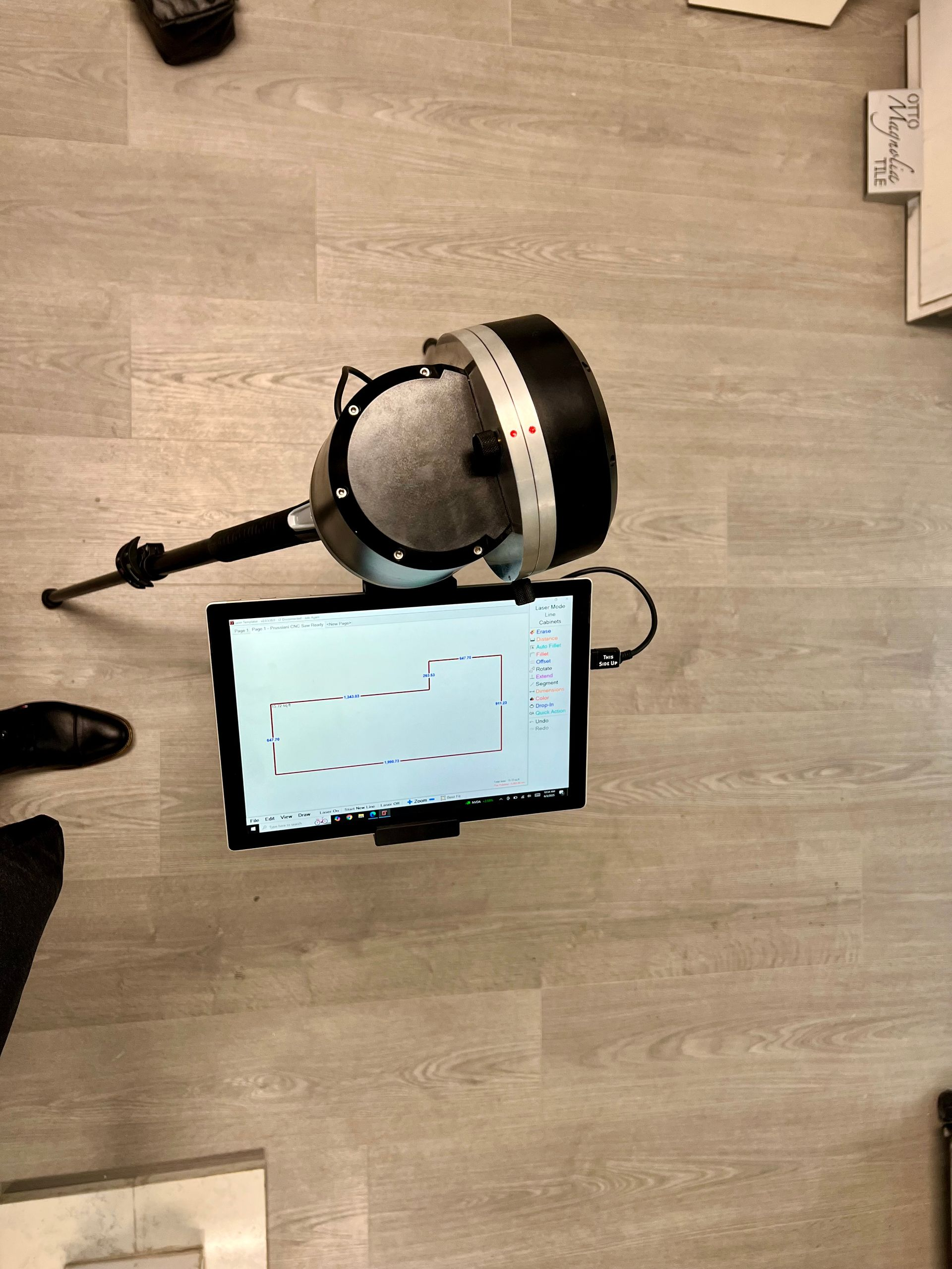 A power laser on a tripod with a tablet on top of it.