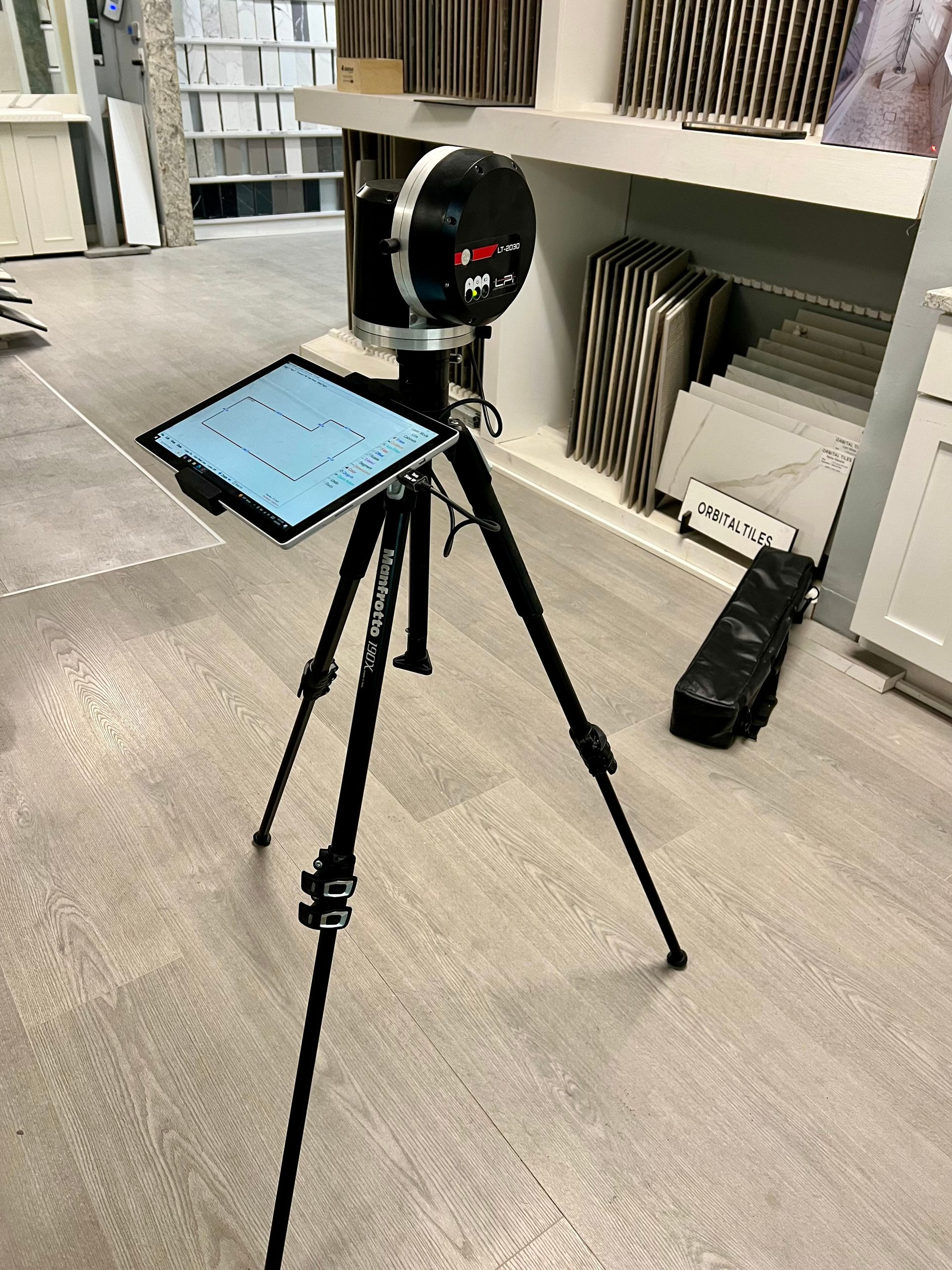 A power laser on a tripod with a tablet on top of it.