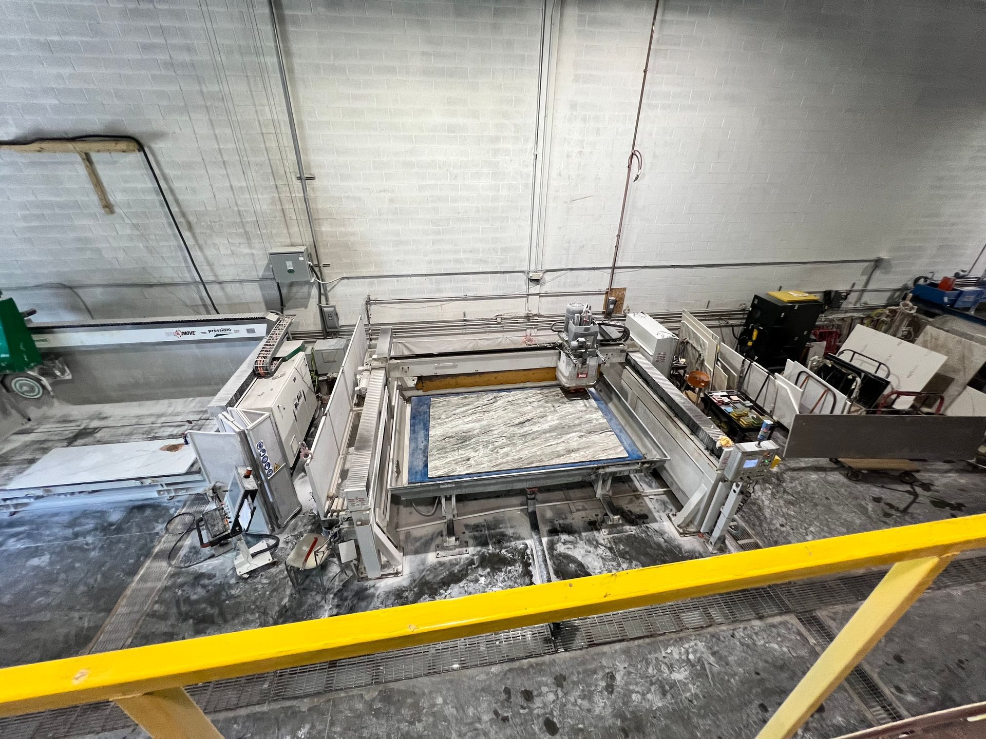 A machine is sitting in a warehouse next to a yellow railing.