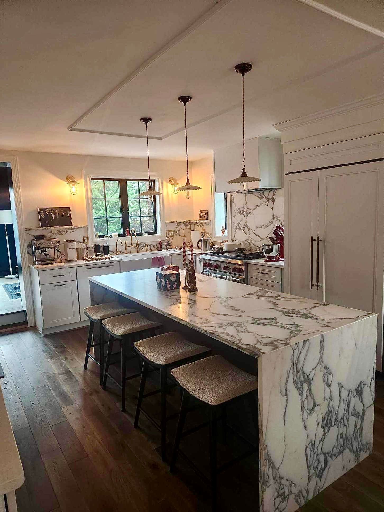 A kitchen with a large island and marble counter tops.