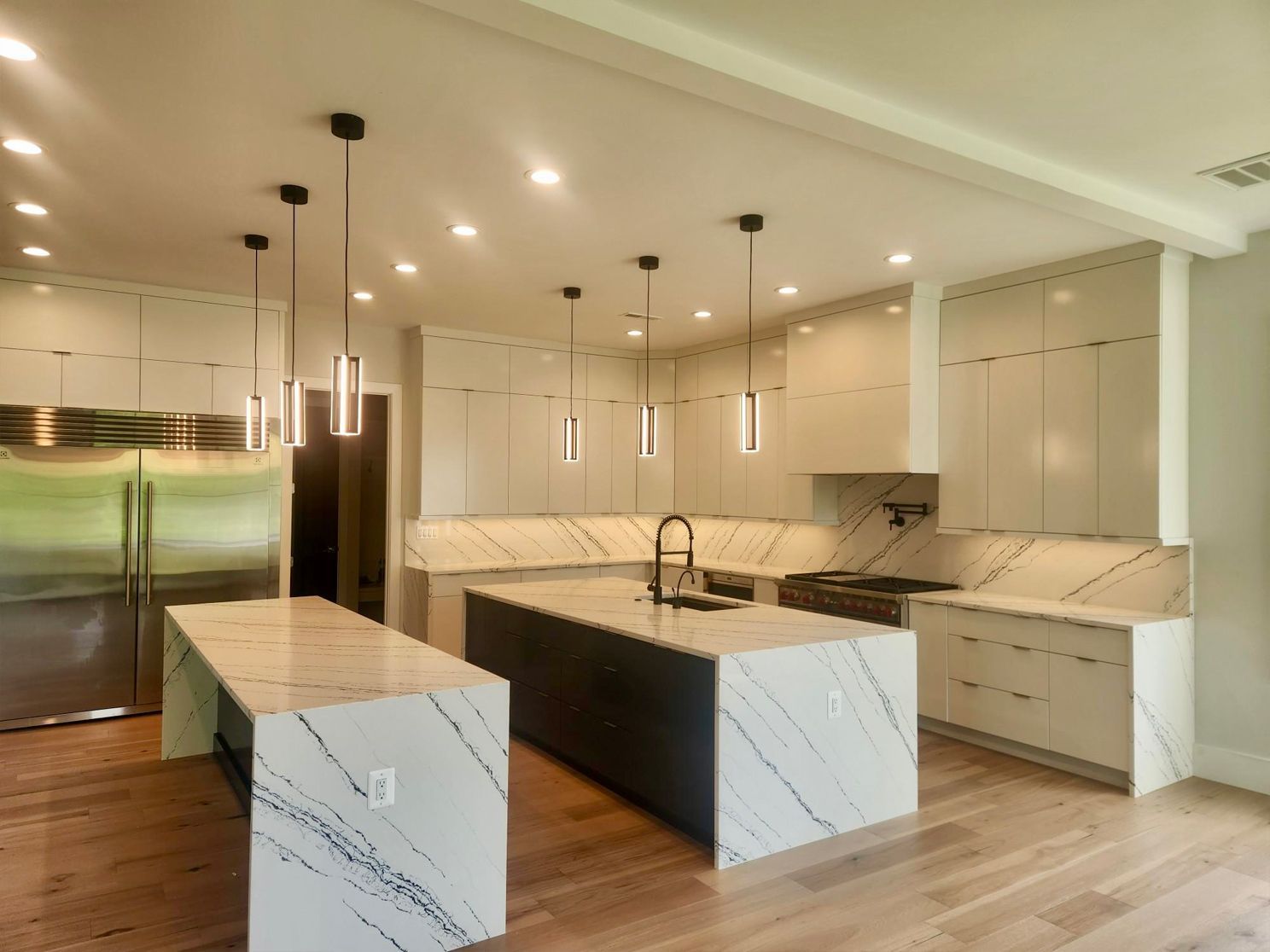 A kitchen with white cabinets , granite counter tops , stainless steel appliances and a large island.