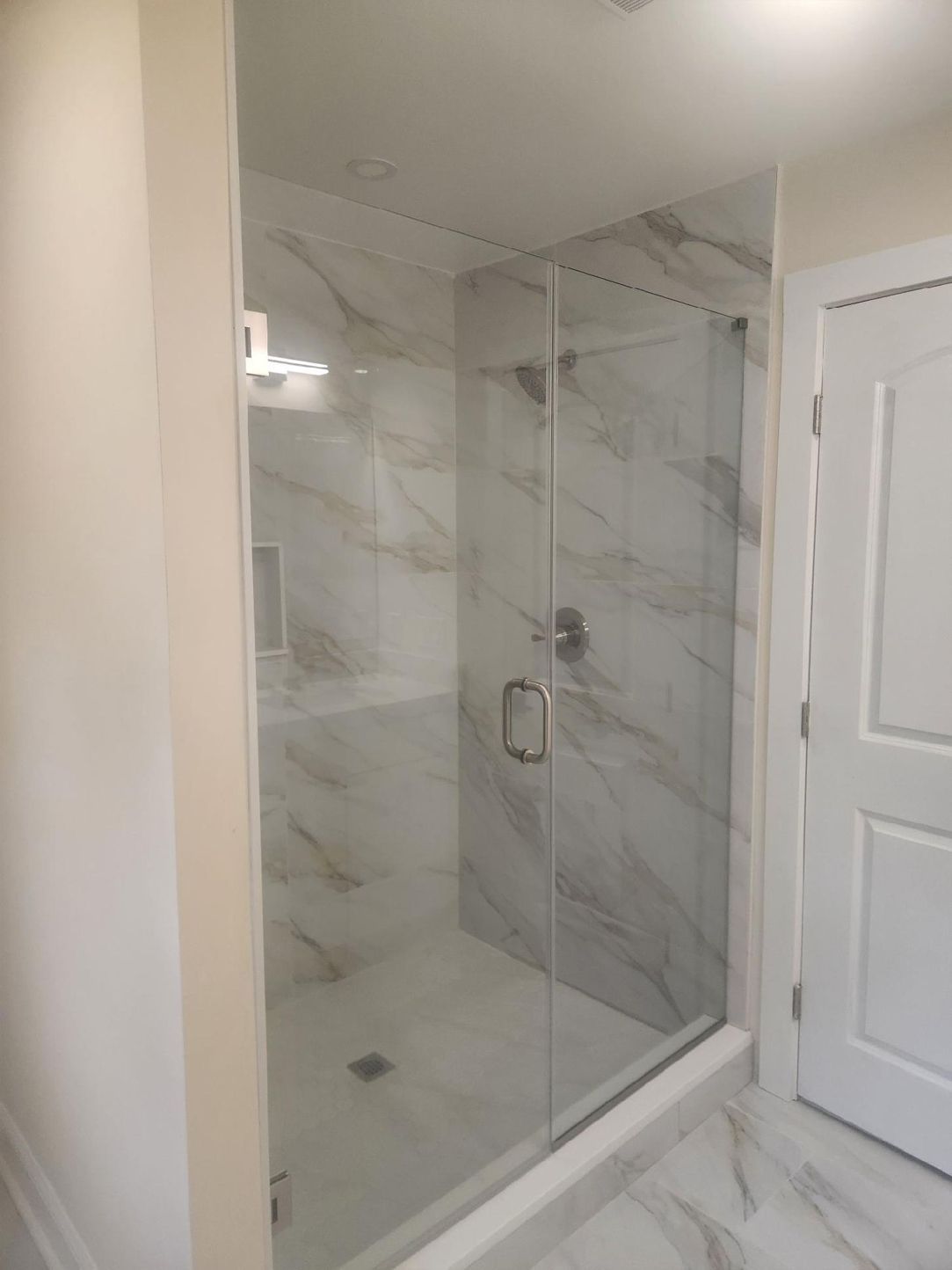 A bathroom with a walk in shower with a glass door