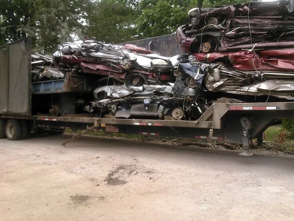 A truck is carrying a large pile of wrecked cars