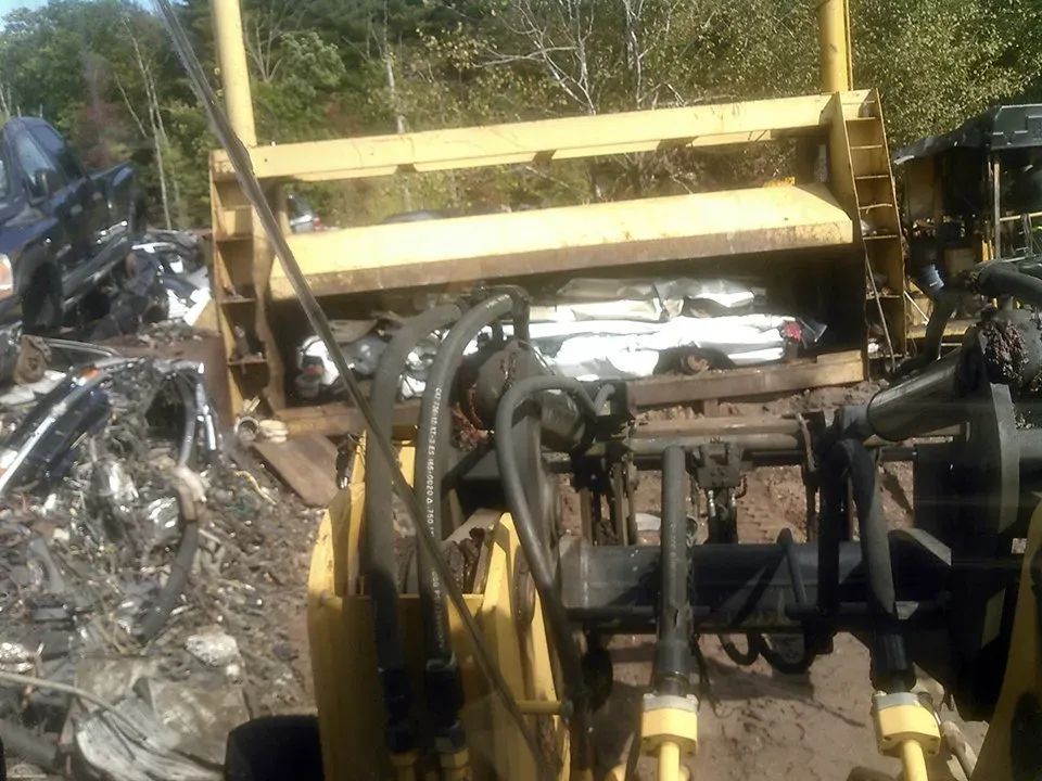 A yellow tractor is sitting in a pile of scrap metal