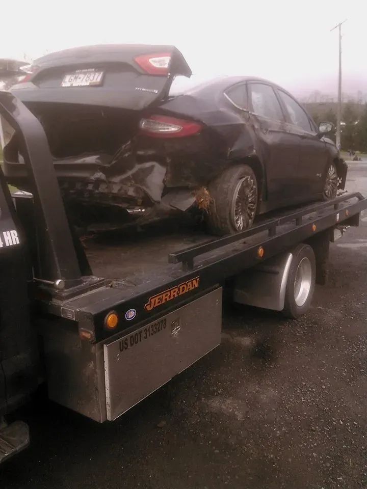 A black car is being towed by a tow truck