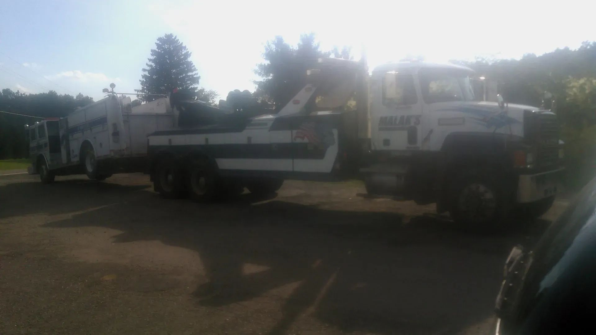 A tow truck with a trailer attached to it is parked in a parking lot